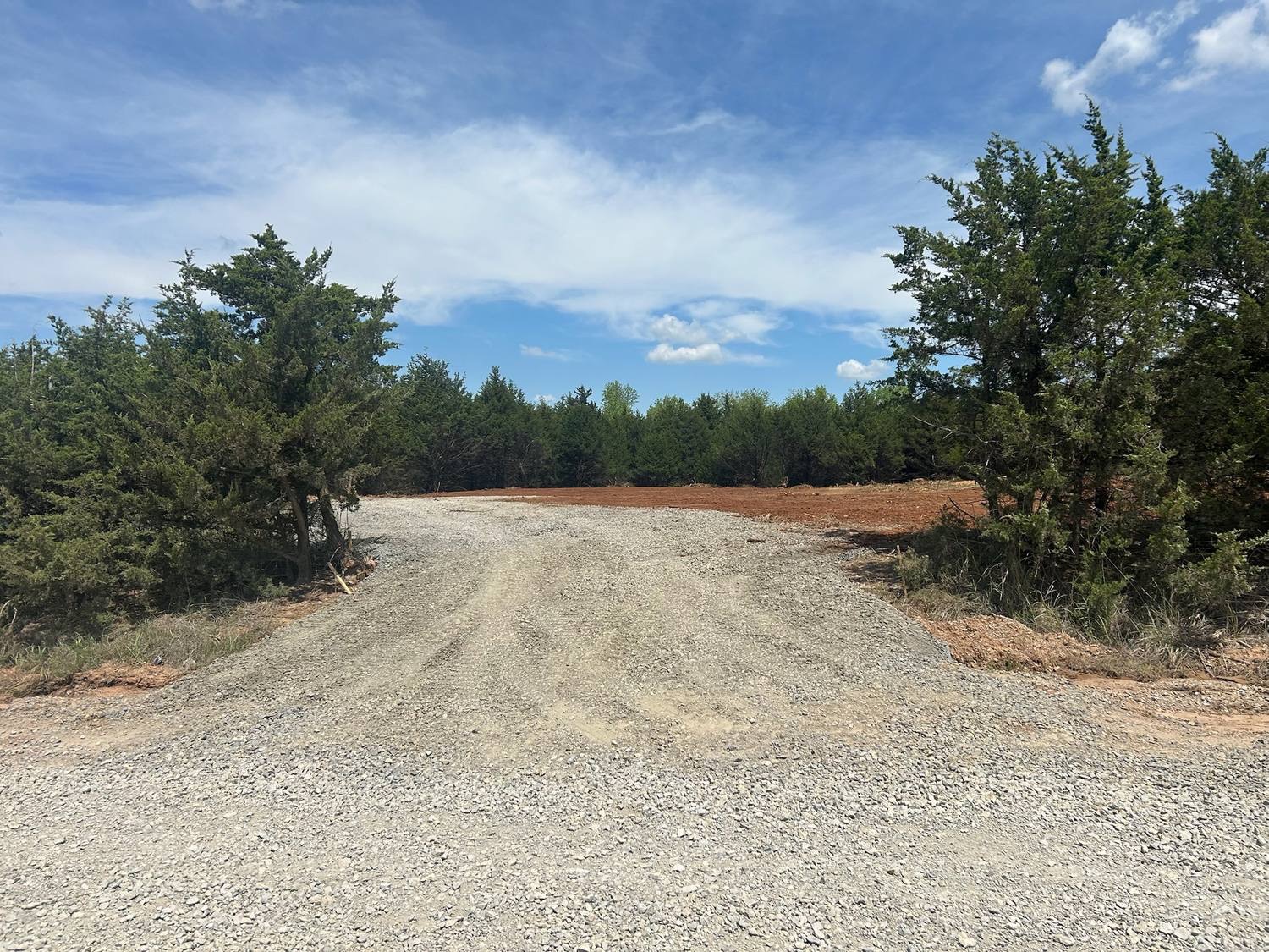 Forestry mulching results in Latimer County, Oklahoma - gravel driveway leading into a cleared cedar tract prepared for pre-construction site work